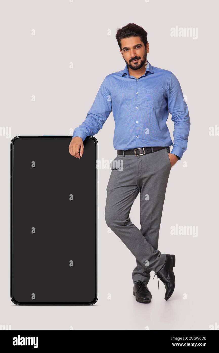 Ritratto di un uomo in abiti formali accanto al telefono cellulare su sfondo bianco. Foto Stock