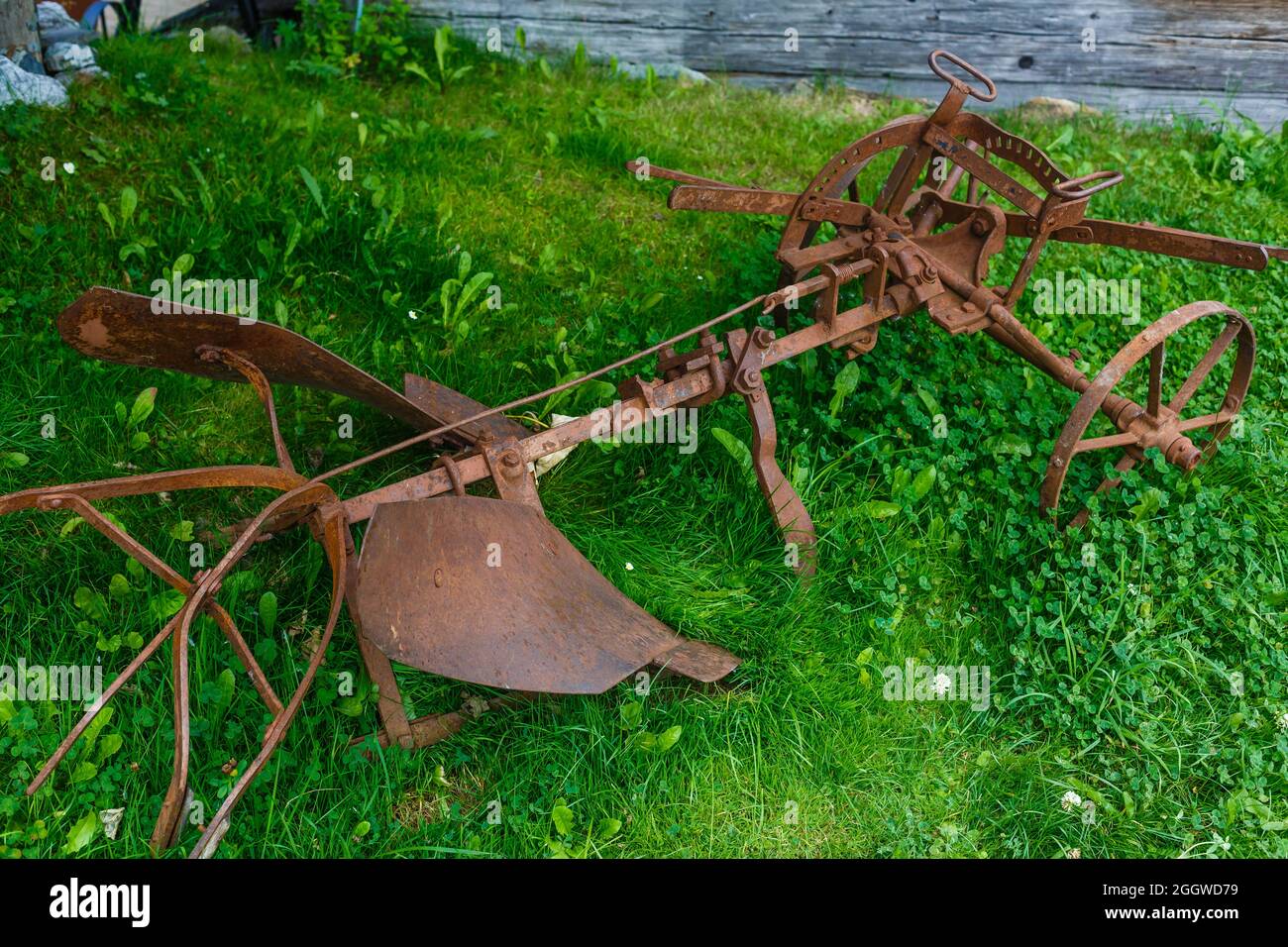 vecchio aratro arrugginito adagiato sull'erba Foto Stock
