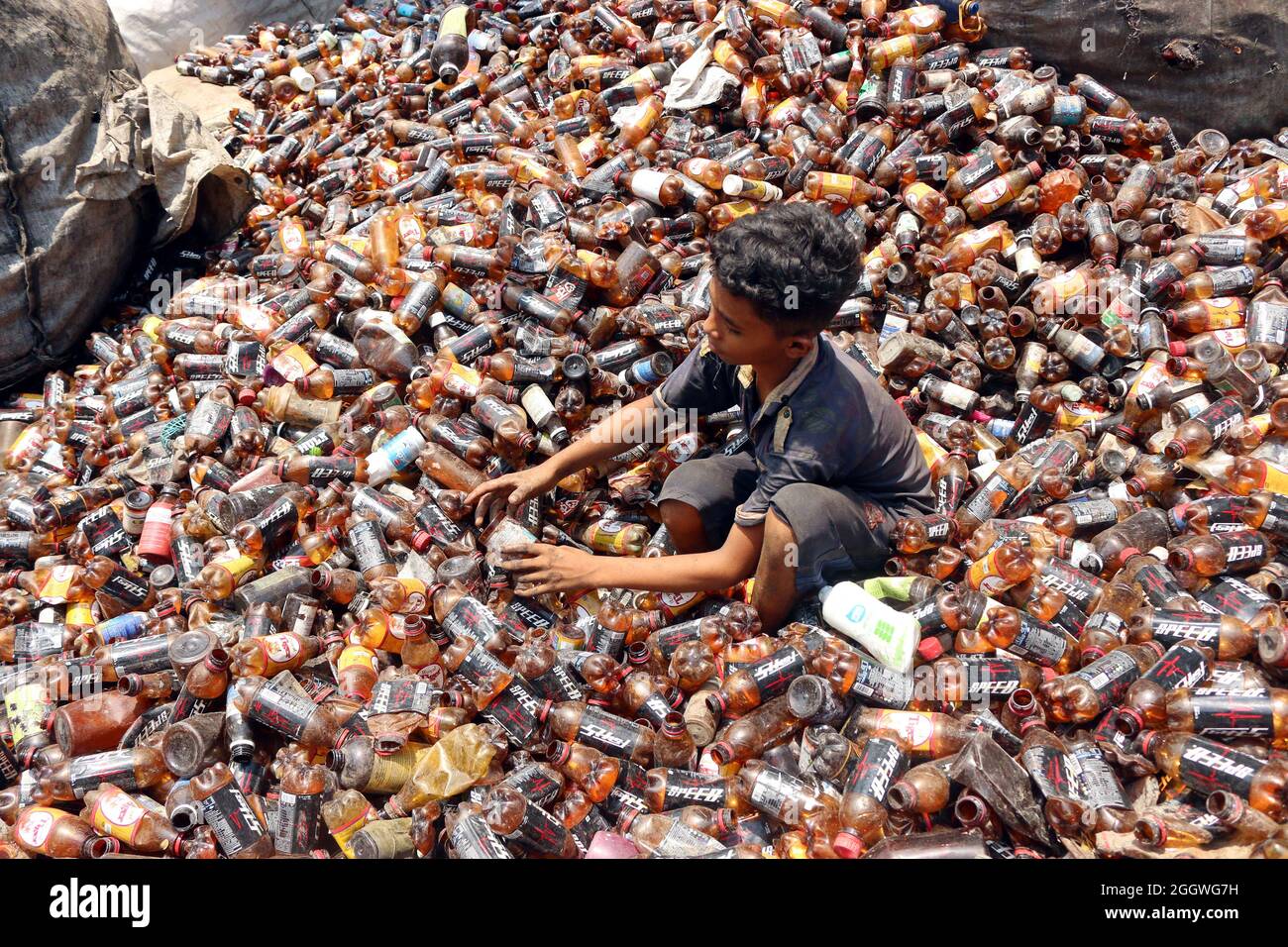 Dhaka, Bangladesh, 03/09/2021, Un bambino separa bottiglie di polietilene tereftalato (PET) in una fabbrica di riciclaggio alla periferia di Dhaka. Il riciclaggio delle bottiglie in plastica è diventato un'attività in crescita negli ultimi due anni e contribuisce a proteggere l'ambiente. Secondo la Bangladesh PET Flakes Manufacturers and Exporters Association (BPFMEA), il Bangladesh esporta in media quasi 30,000 tonnellate di fiocchi di bottiglie di PET principalmente in Cina, Corea del Sud e Taiwan per un valore di 14 milioni di dollari l'anno. Il 3 settembre 2021. (Foto di Habibur Rahman / Eyepix Group) Foto Stock