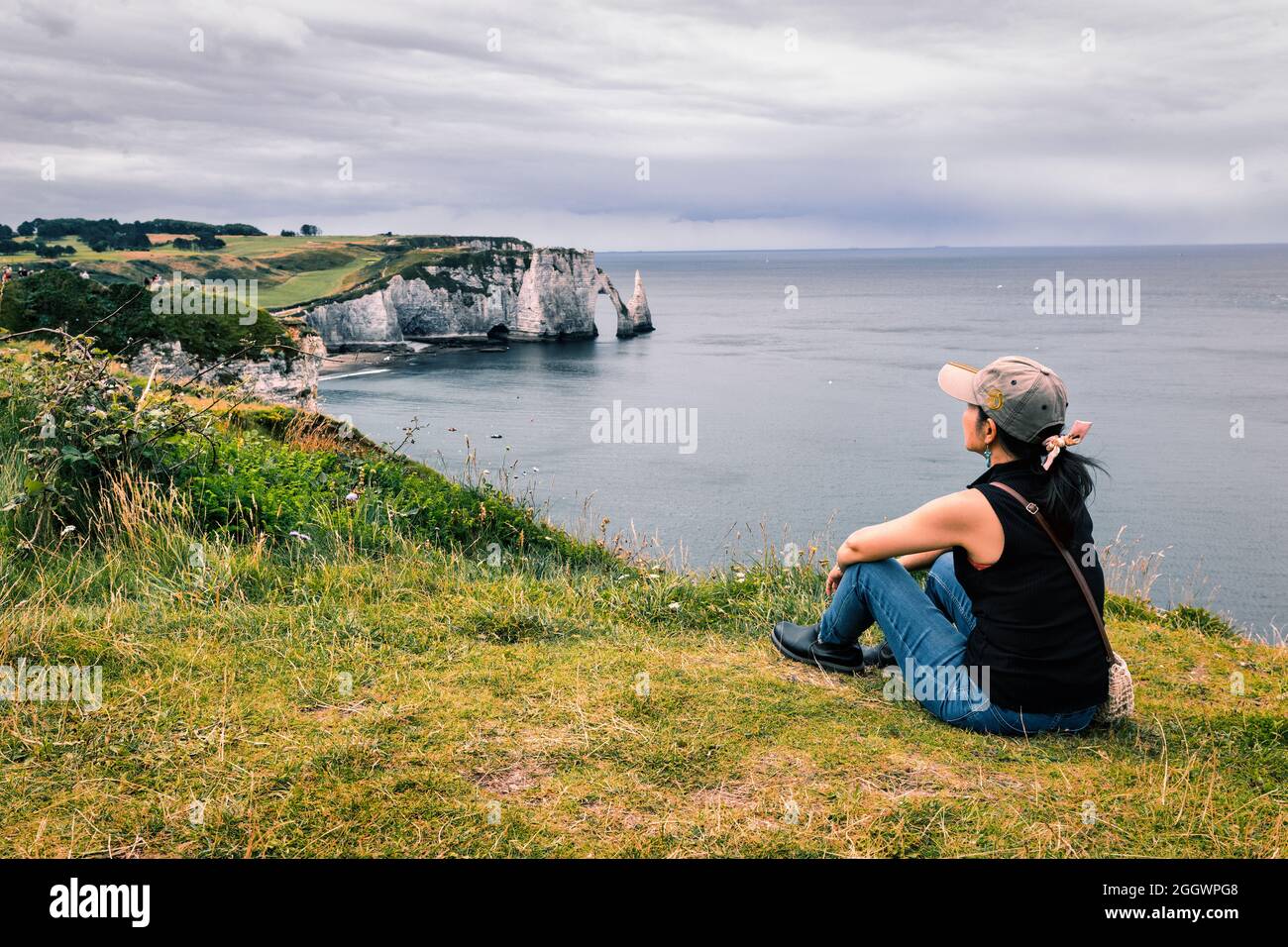 Donna che contempla il paesaggio della baia di Etretat, Normandia, Francia Foto Stock