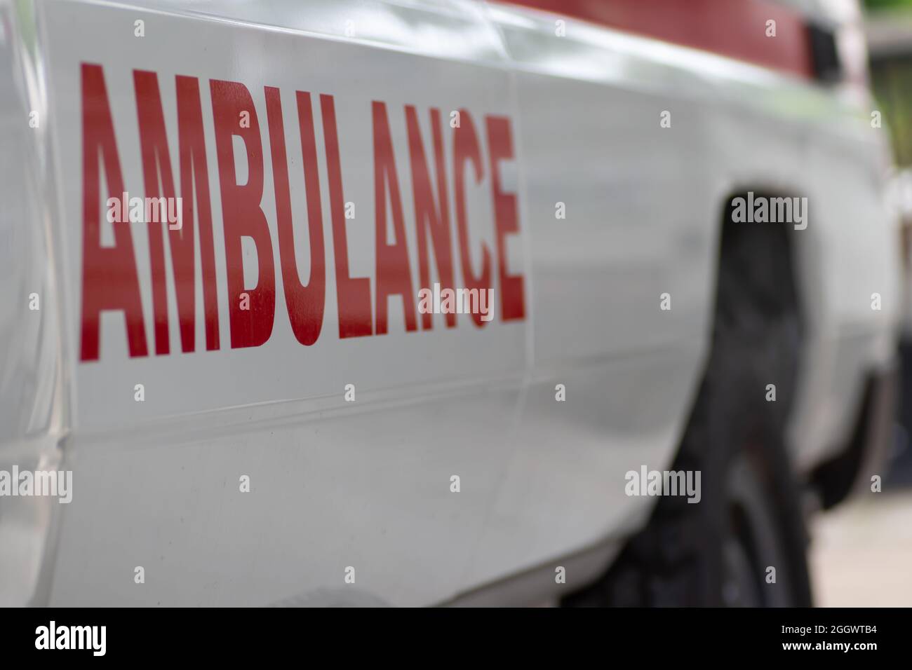 Primo piano del veicolo ambulanza pronto per la partenza per l'assistenza medica di emergenza, con croce rossa medica visibile e luci di emergenza e sirena Foto Stock