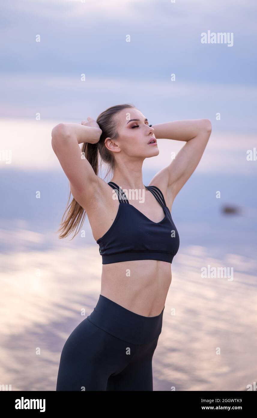 foto concettuale di una giovane ragazza che si estende sulla spiaggia al tramonto Foto Stock