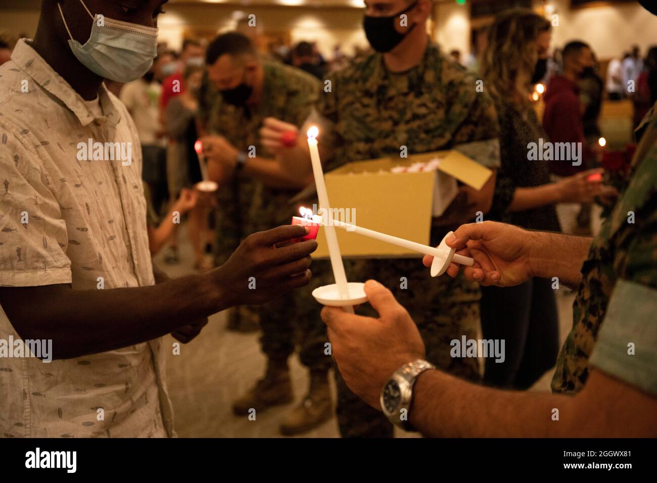 I membri del servizio e le famiglie ricevono e illuminano le candele durante un servizio di preghiera commemorativo e una veglia a lume di candela a bordo della base del corpo Marino Hawaii, 29 agosto 2021. L'evento si è tenuto per onorare e ricordare i 13 membri del servizio che sono stati uccisi in Afghanistan il 26 agosto 2021. (STATI UNITI Foto del corpo marino di Gunnery Sgt. Orlando Perez) Foto Stock