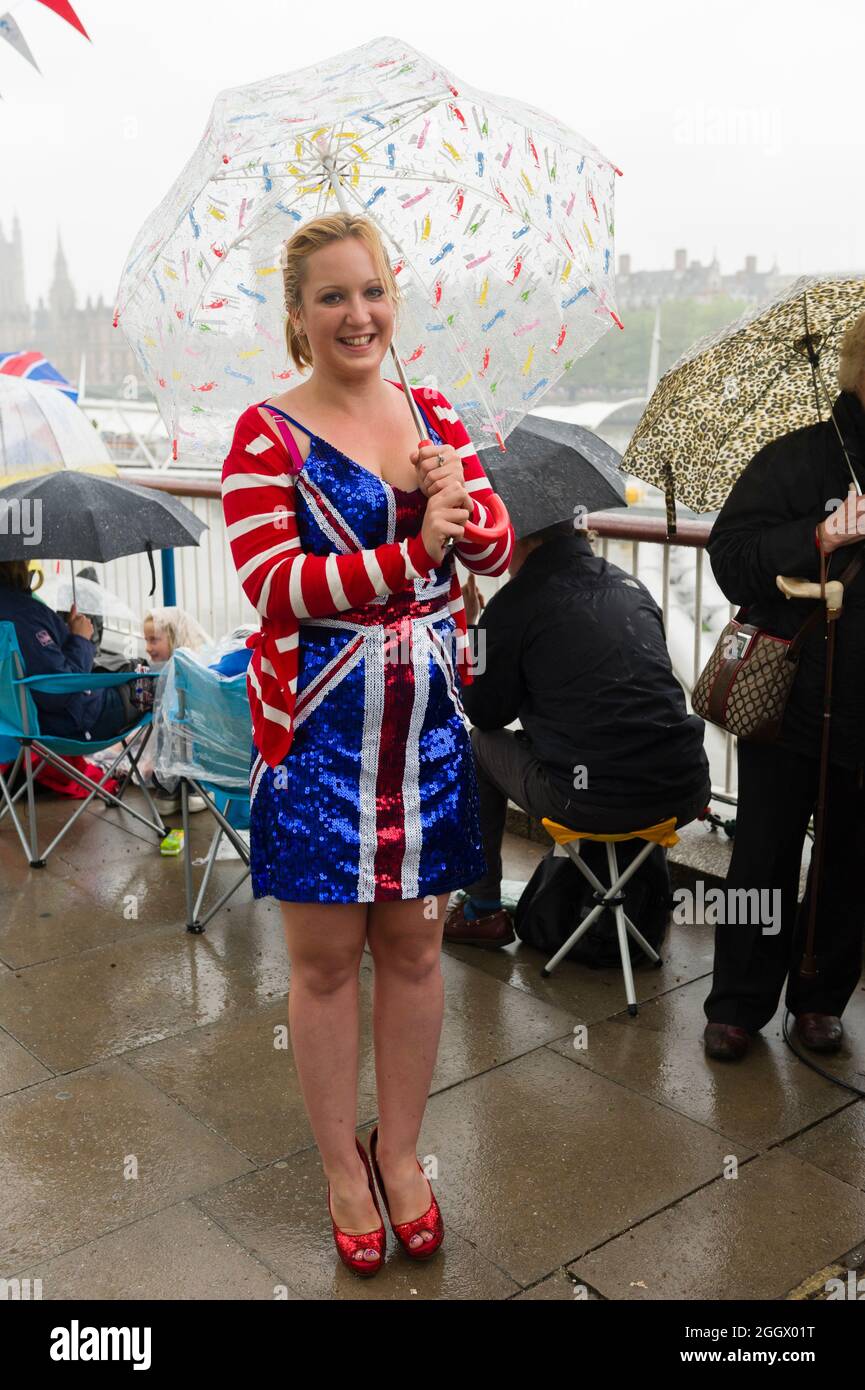 Uno spettatore soleggiato in Union Jack vestire in attesa di pioggia per il Tamigi Diamond Jubilee Pageant per passare la South Bank, Londra. Il Pageant era composto da centinaia di barche che navigavano dal ponte di Battersea al ponte della Torre per celebrare i 60 anni della regina Elisabetta II sul trono. Milioni di persone hanno fiancheggiato le rive del Tamigi per guardare lo spettacolo. South Bank, Londra, Regno Unito. 3 Giu 2012 Foto Stock