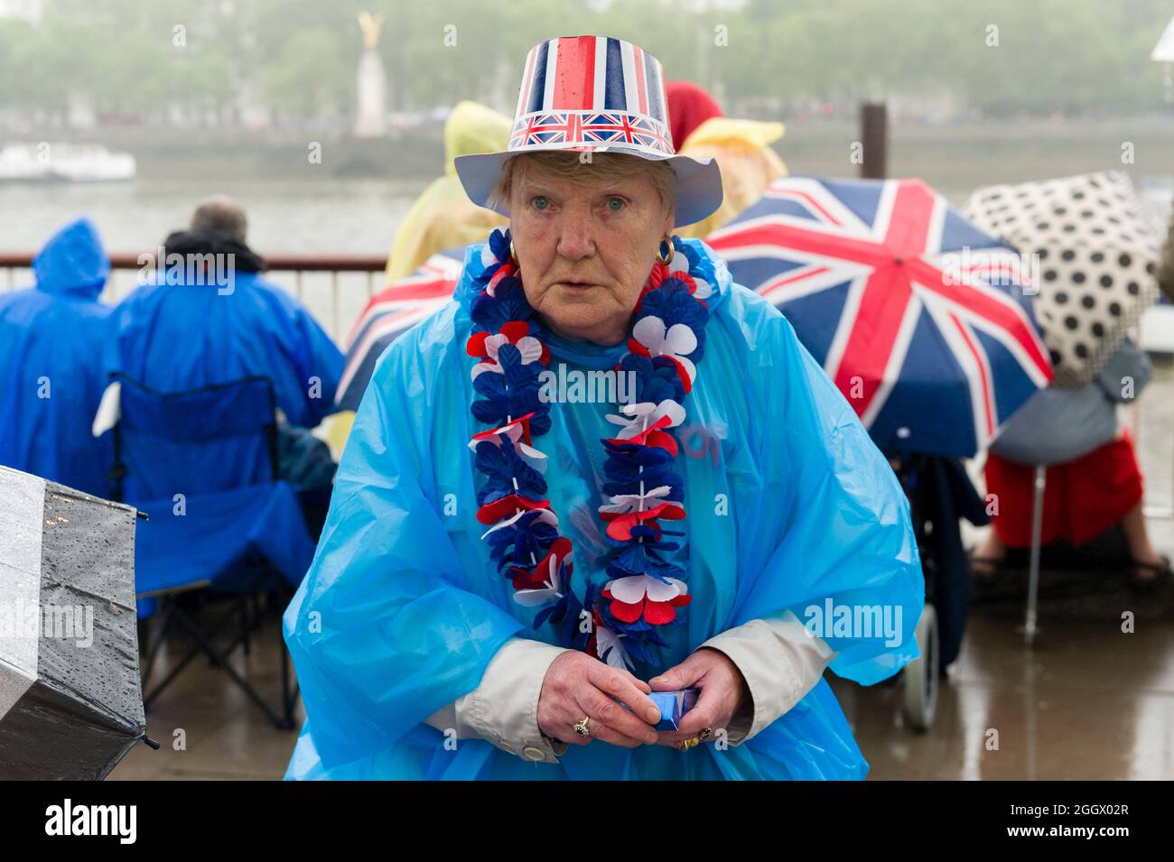 Spettatori in attesa della pioggia per il Thames Diamond Jubilee Pageant per passare la South Bank, Londra. Il Pageant era composto da centinaia di barche che navigavano dal ponte di Battersea al ponte della Torre per celebrare i 60 anni della regina Elisabetta II sul trono. Milioni di persone hanno fiancheggiato le rive del Tamigi per guardare lo spettacolo. South Bank, Londra, Regno Unito. 3 Giu 2012 Foto Stock