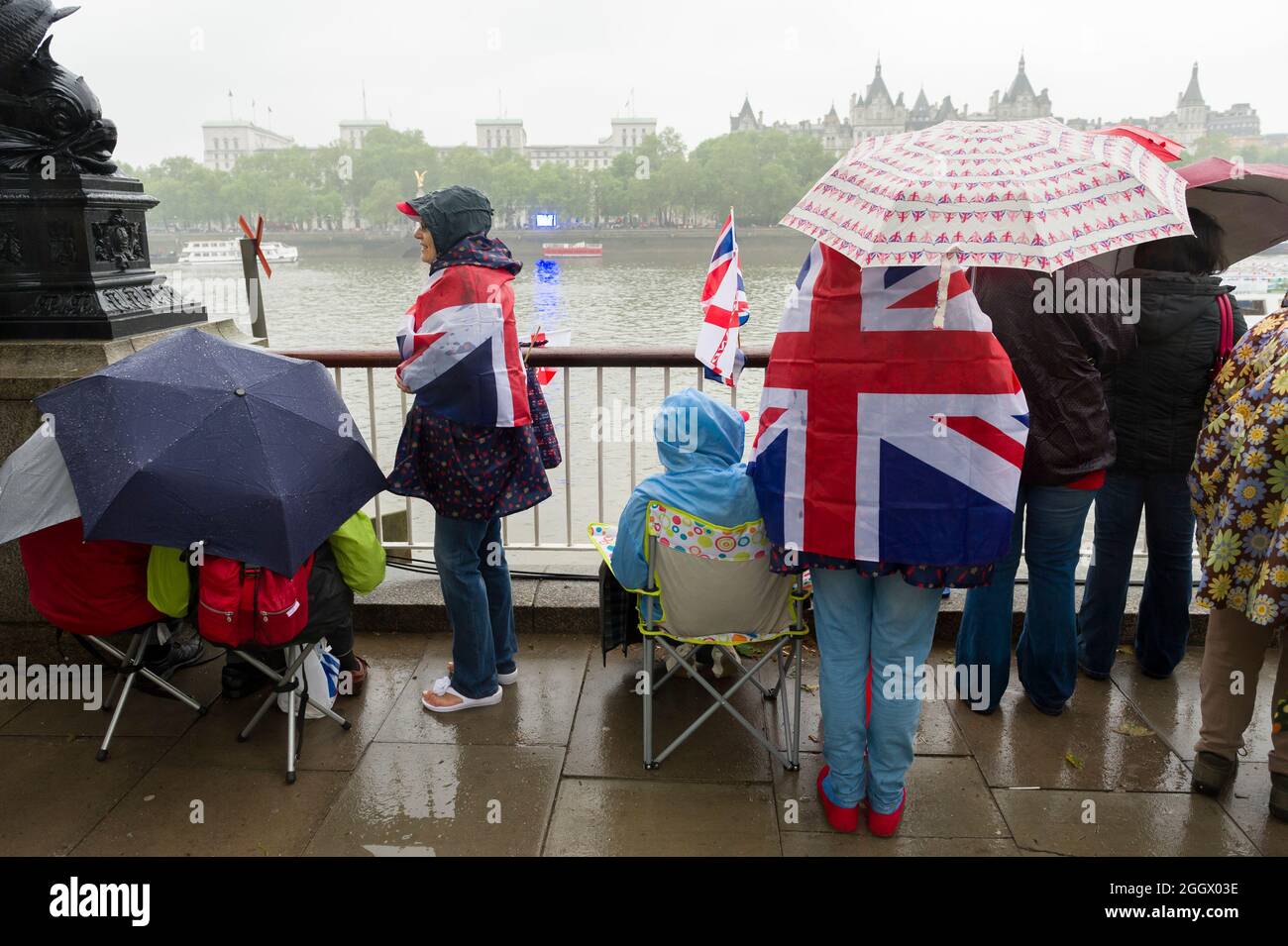 Spettatori in attesa della pioggia per il Thames Diamond Jubilee Pageant per passare la South Bank, Londra. Il Pageant era composto da centinaia di barche che navigavano dal ponte di Battersea al ponte della Torre per celebrare i 60 anni della regina Elisabetta II sul trono. Milioni di persone hanno fiancheggiato le rive del Tamigi per guardare lo spettacolo. South Bank, Londra, Regno Unito. 3 Giu 2012 Foto Stock