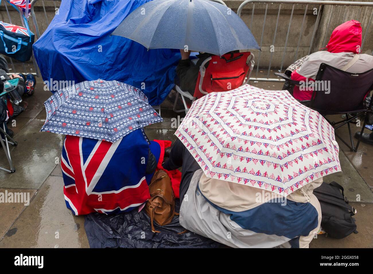 Spettatori in attesa della pioggia per il Thames Diamond Jubilee Pageant per passare la South Bank, Londra. Il Pageant era composto da centinaia di barche che navigavano dal ponte di Battersea al ponte della Torre per celebrare i 60 anni della regina Elisabetta II sul trono. Milioni di persone hanno fiancheggiato le rive del Tamigi per guardare lo spettacolo. South Bank, Londra, Regno Unito. 3 Giu 2012 Foto Stock