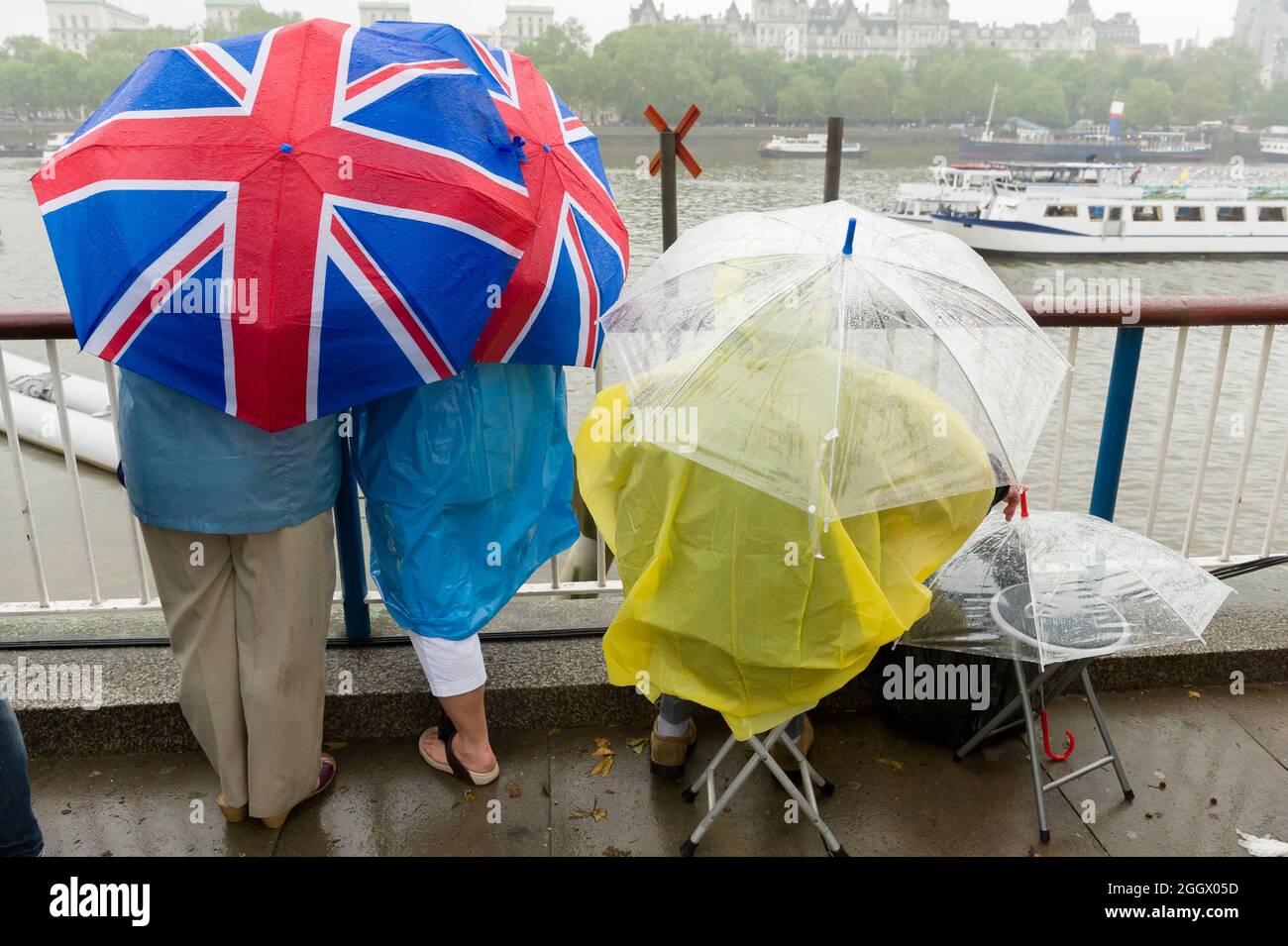 Spettatori in attesa sotto gli ombrelli Union Jack sotto la pioggia per il Tamigi Diamond Jubilee Pageant per passare la South Bank, Londra. Il Pageant era composto da centinaia di barche che navigavano dal ponte di Battersea al ponte della Torre per celebrare i 60 anni della regina Elisabetta II sul trono. Milioni di persone hanno fiancheggiato le rive del Tamigi per guardare lo spettacolo. South Bank, Londra, Regno Unito. 3 Giu 2012 Foto Stock