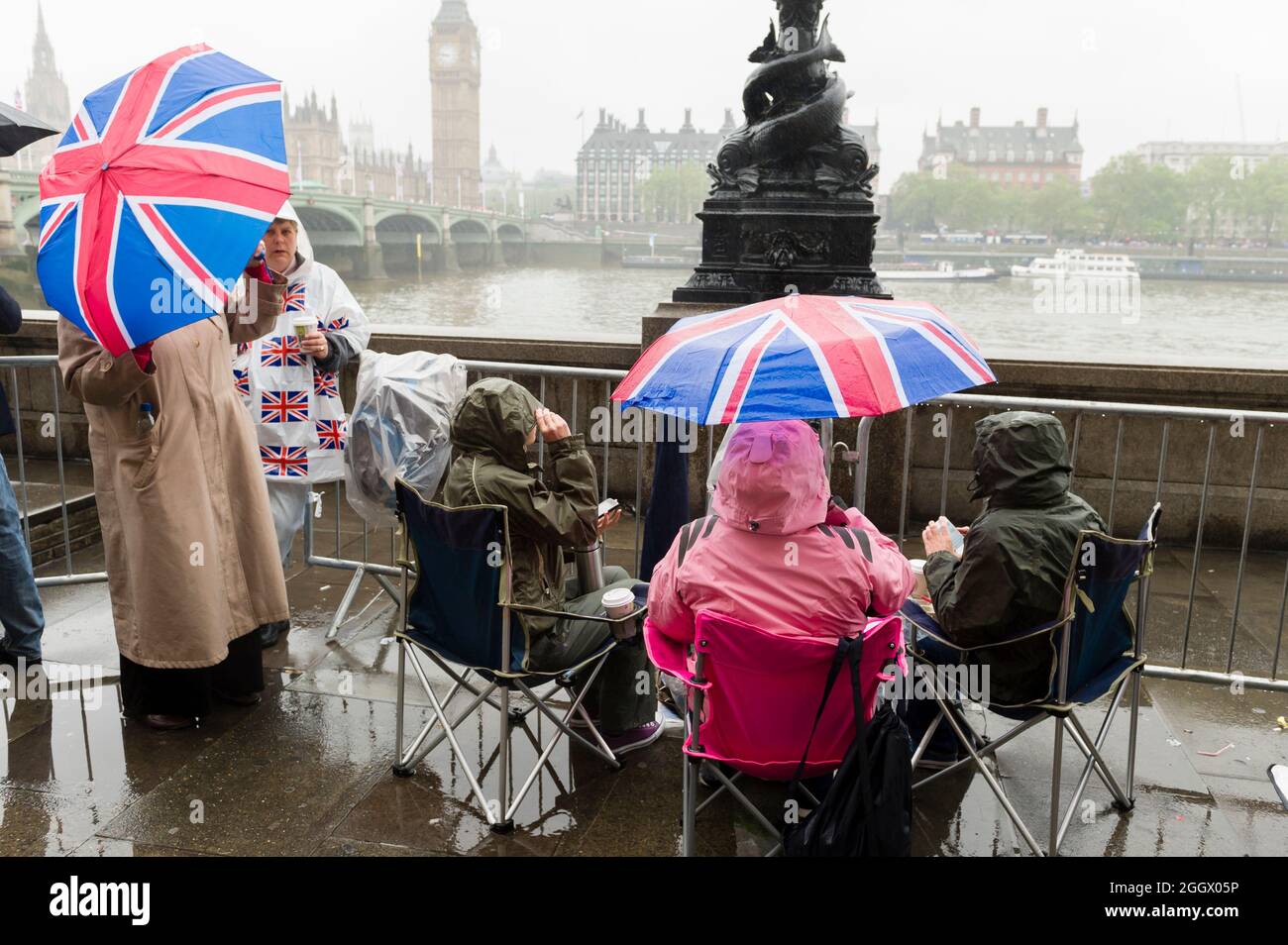 Spettatori in attesa sotto gli ombrelli Union Jack sotto la pioggia per il Tamigi Diamond Jubilee Pageant per passare la South Bank, Londra. Il Pageant era composto da centinaia di barche che navigavano dal ponte di Battersea al ponte della Torre per celebrare i 60 anni della regina Elisabetta II sul trono. Milioni di persone hanno fiancheggiato le rive del Tamigi per guardare lo spettacolo. South Bank, Londra, Regno Unito. 3 Giu 2012 Foto Stock
