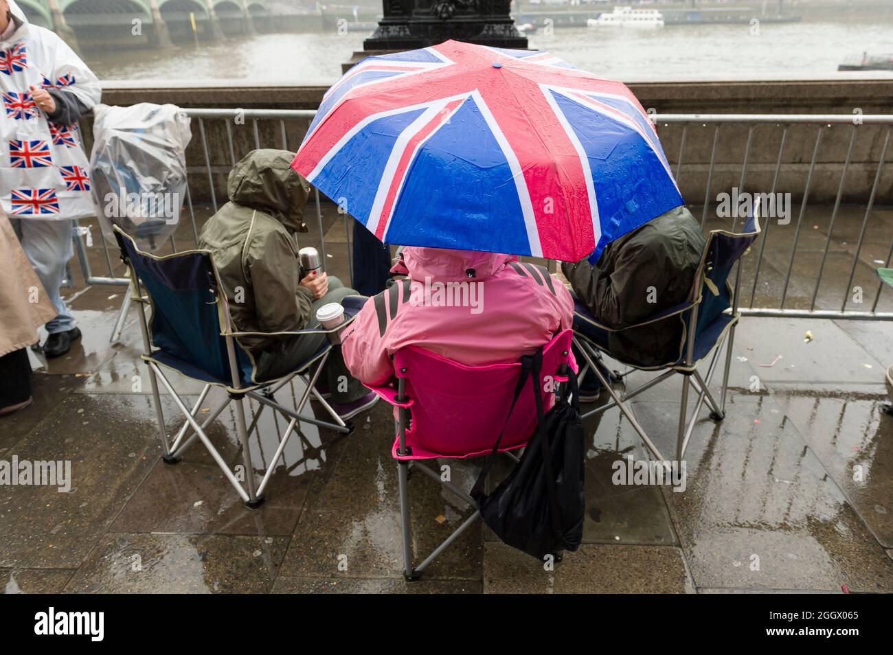 Spettatori in attesa della pioggia per il Thames Diamond Jubilee Pageant per passare la South Bank, Londra. Il Pageant era composto da centinaia di barche che navigavano dal ponte di Battersea al ponte della Torre per celebrare i 60 anni della regina Elisabetta II sul trono. Milioni di persone hanno fiancheggiato le rive del Tamigi per guardare lo spettacolo. South Bank, Londra, Regno Unito. 3 Giu 2012 Foto Stock