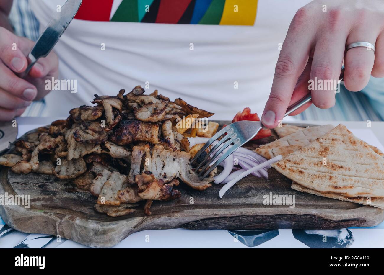 Uomo non identificato che mangia Gyros, un piatto tradizionale greco a base di carne cucinata su una rotisserie verticale, mentre in vacanza a Mykonos, Grecia. Foto Stock