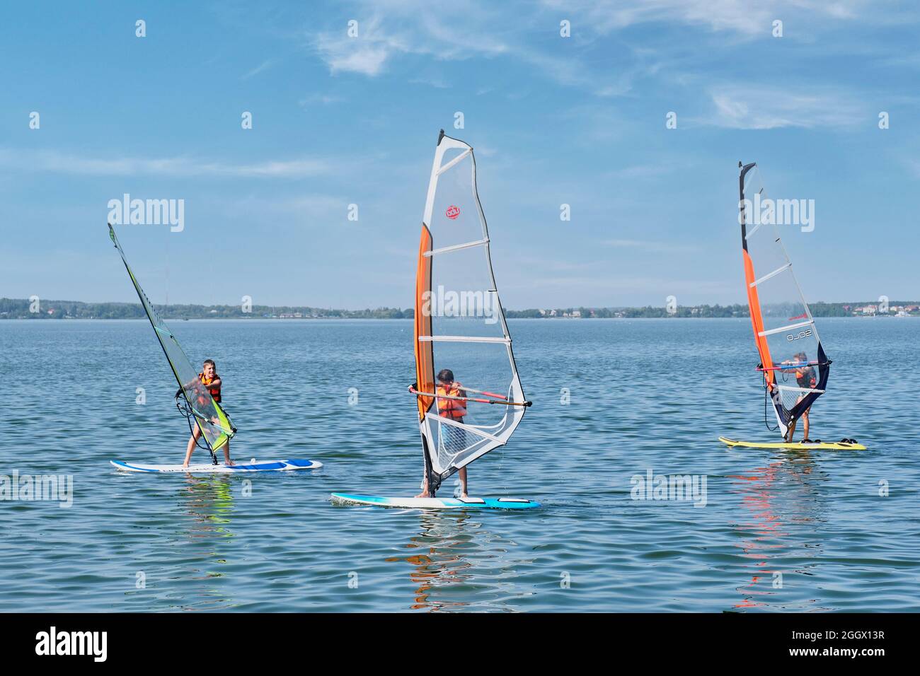 Corsi di windsurf. I bambini galleggiano a bordo con vela sul lago Foto Stock