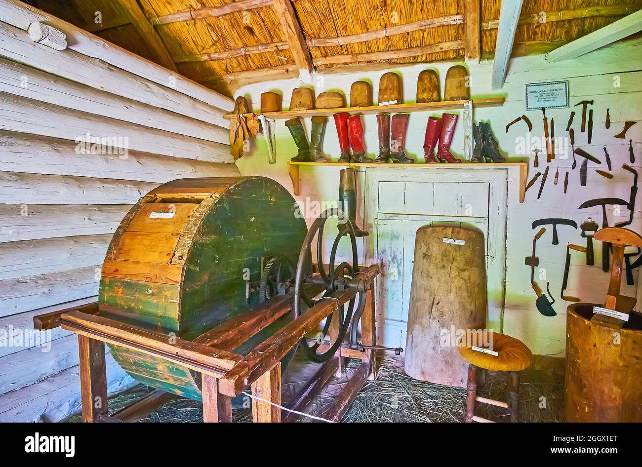 PEREIASLAV, UCRAINA - 22 MAGGIO 2021: Il laboratorio medievale di conceria con tamburo abbronzante in pelle, strumenti per conciatori ed esempi di stivali artigianali d'epoca Foto Stock