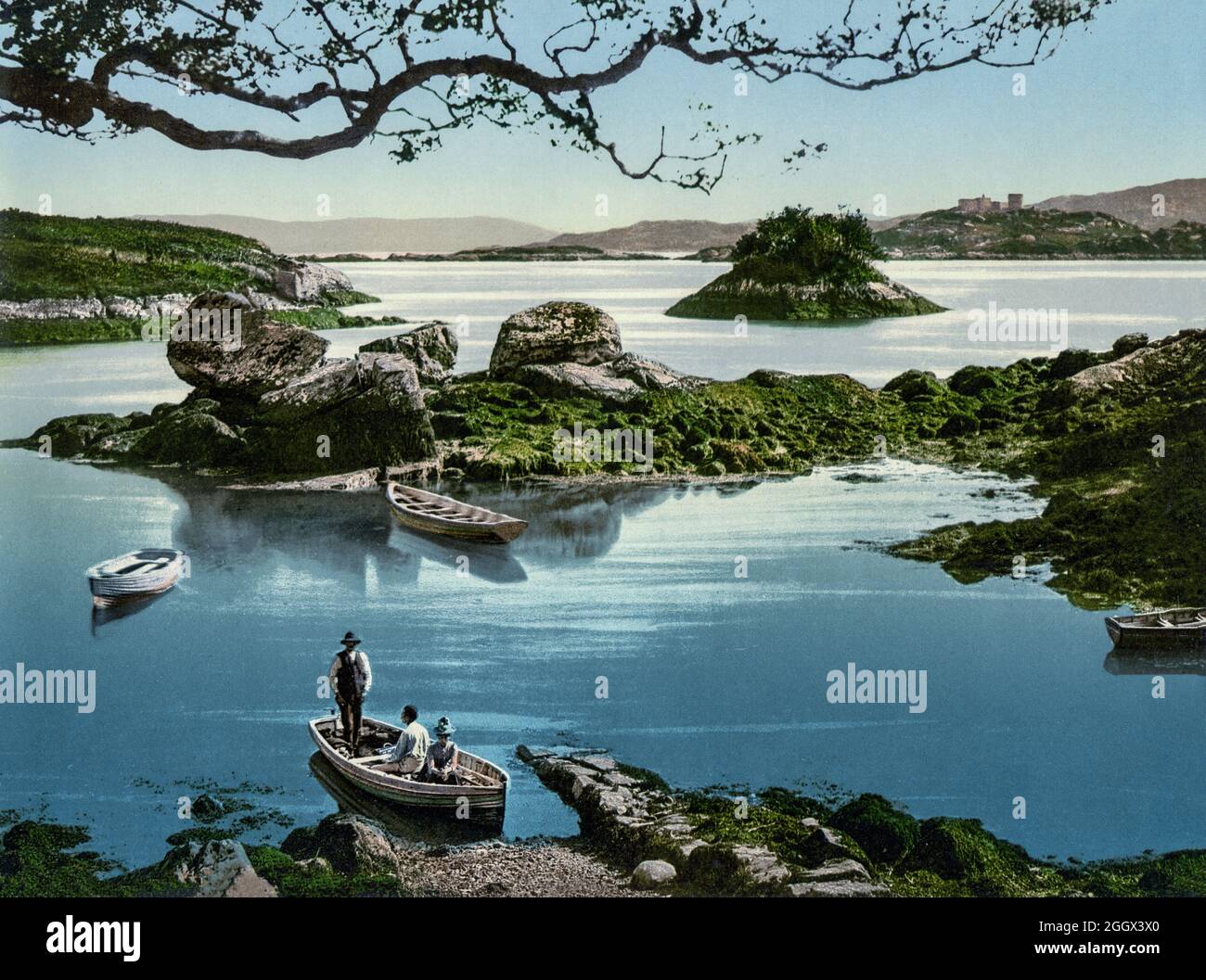 Una vista dei primi del XX secolo di un boatman che porta i turisti per un'escursione a Kenmare Bay, sulla contea di Cork e Kerry Borders, Irlanda Foto Stock