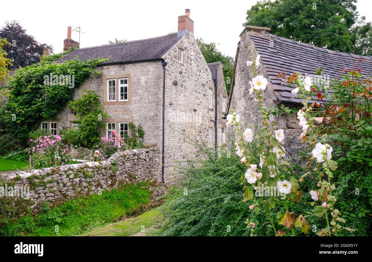 Guardando in un bel giardino cottage nel Derbyshire villaggio di Parwich. I fiori in fiore si trovano oltre il muro di pietra. Foto Stock Guardando in un bel giardino cottage nel Derbyshire villaggio di Parwich. I fiori in fiore si trovano oltre il muro di pietra. Foto Stock
