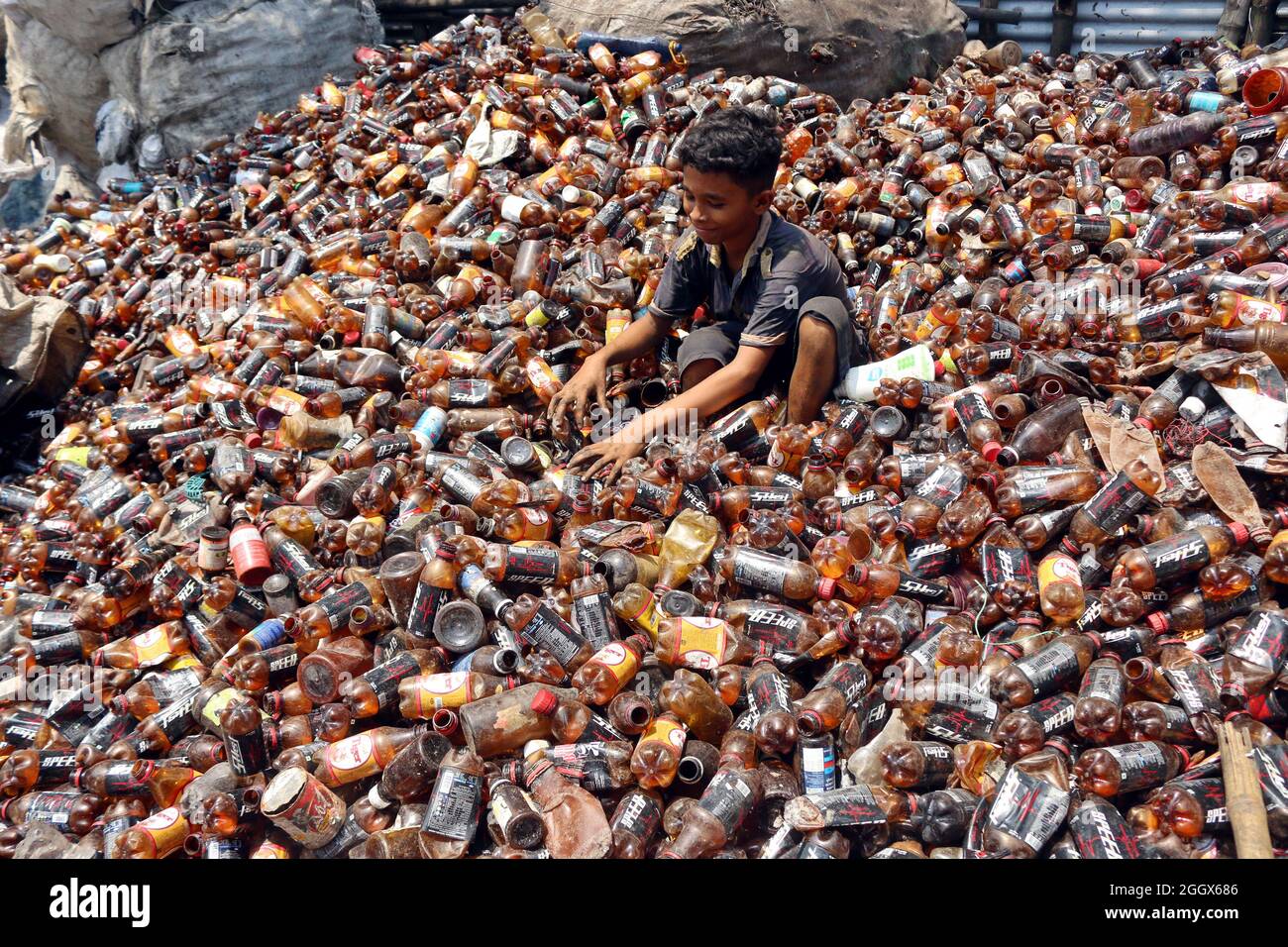 Non esclusiva: DHAKA, BANGLADESH -3 SETTEMBRE: Un bambino separa le bottiglie di polietilene tereftalato (PET) in una fabbrica di riciclaggio alla periferia di Foto Stock