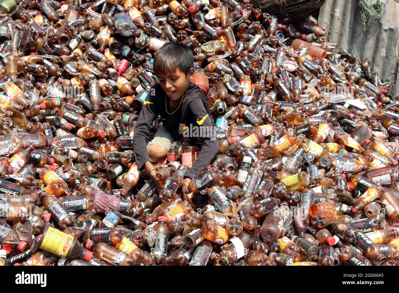 Non esclusiva: DHAKA, BANGLADESH -3 SETTEMBRE: Un bambino separa le bottiglie di polietilene tereftalato (PET) in una fabbrica di riciclaggio alla periferia di Foto Stock