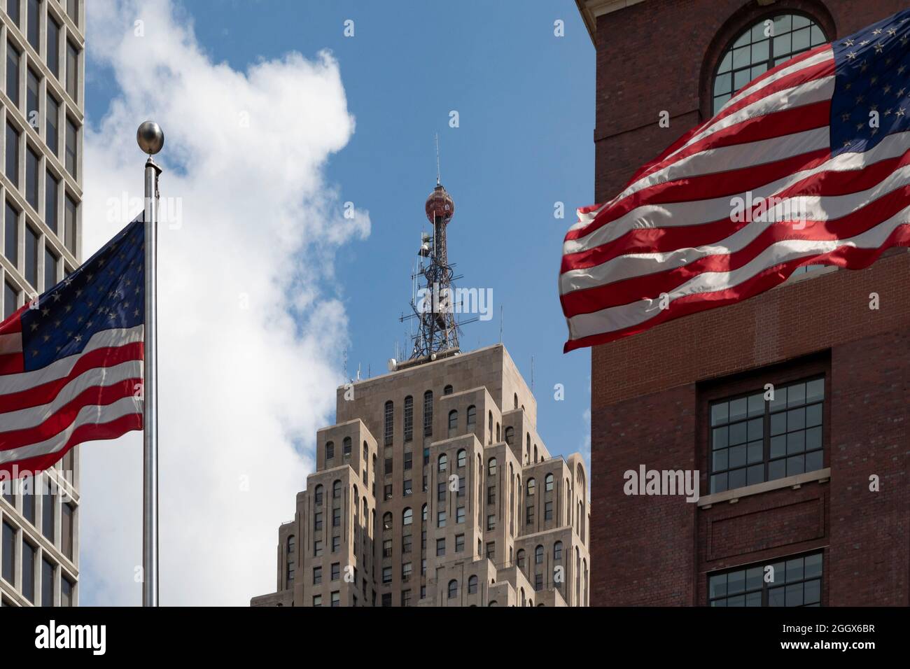 Detroit, Michigan - il Penobscot Building, incorniciato da bandiere che volano davanti al centro congressi TCF. L'edificio a 47 piani era l'ottavo più alto Foto Stock
