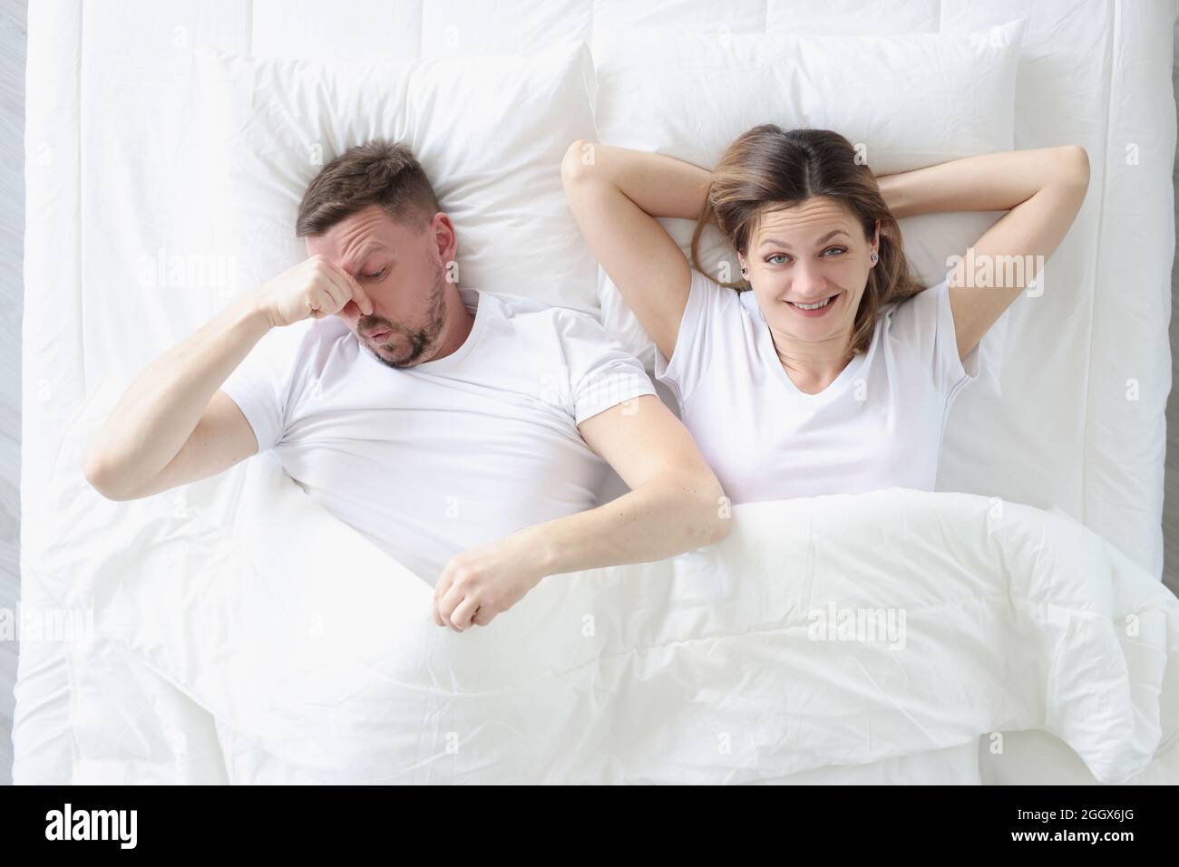 Coppia sposata sdraiata nel letto. Uomo che gli copriva il naso con la mano Foto Stock