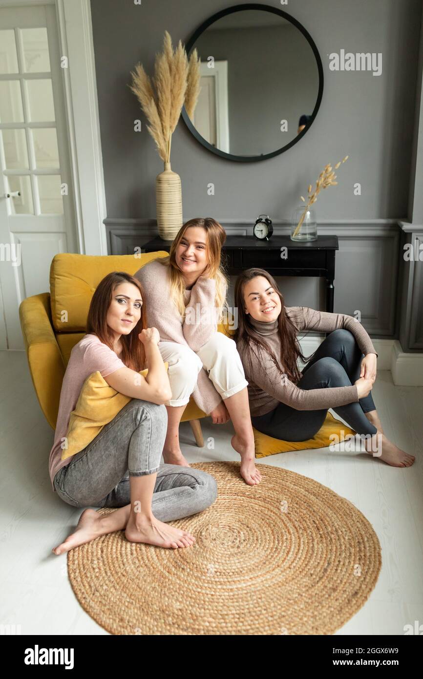 Tre belle girlfriends seduti sul divano, che parlano eccitato, sorridente Foto Stock
