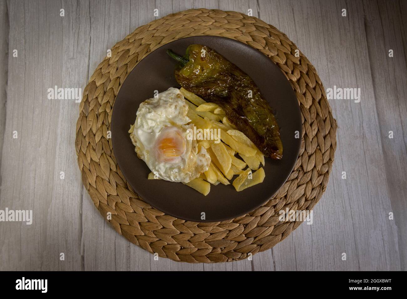 Patate fritte con uova fritte e pepe fritto, un alimento molto richiesto nel sud della Spagna. Tutto fatto con olio d'oliva. Vista dall'alto Foto Stock