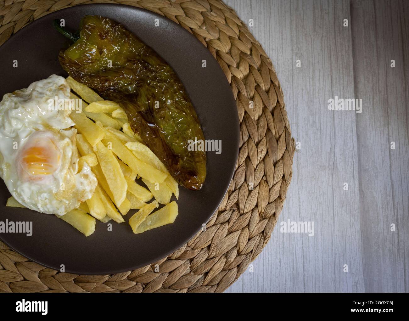 Patate fritte con uova fritte e pepe fritto, un alimento molto richiesto nel sud della Spagna. Tutto fatto con olio d'oliva. Vista dall'alto Foto Stock