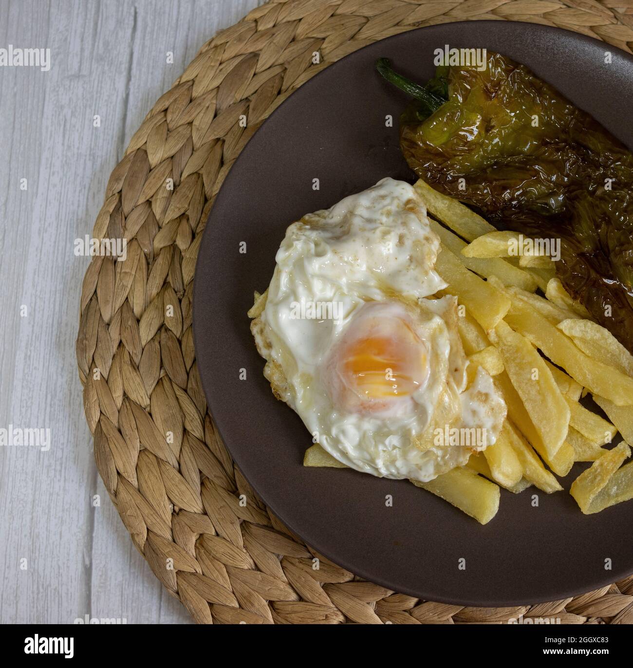 Patate fritte con uova fritte e pepe fritto, un alimento molto richiesto nel sud della Spagna. Tutto fatto con olio d'oliva. Vista dall'alto Foto Stock