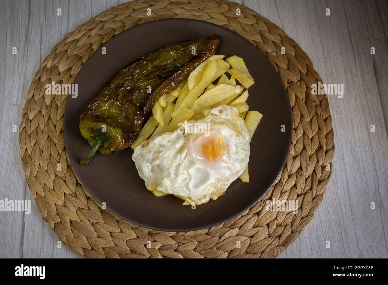 Patate fritte con uova fritte e pepe fritto, un alimento molto richiesto nel sud della Spagna. Tutto fatto con olio d'oliva. Vista dall'alto Foto Stock