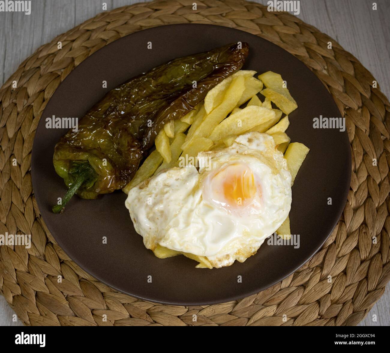 Patate fritte con uova fritte e pepe fritto, un alimento molto richiesto nel sud della Spagna. Tutto fatto con olio d'oliva. Vista dall'alto Foto Stock