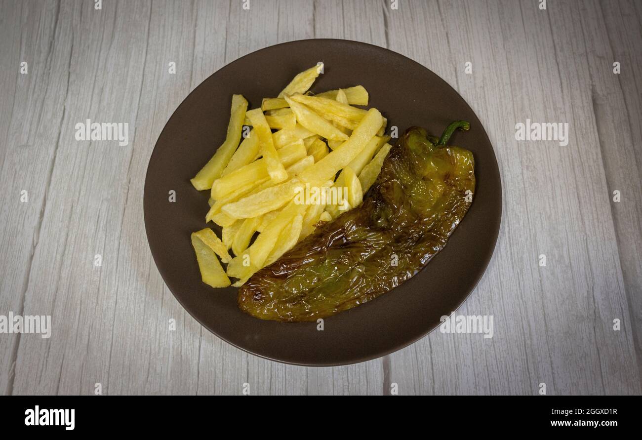 Patatine fritte con peperoni fritti, un alimento molto popolare nel sud della Spagna. Le patate non devono essere congelate e tutte fatte in casa. Tutto fatto con olio d'oliva. Foto Stock