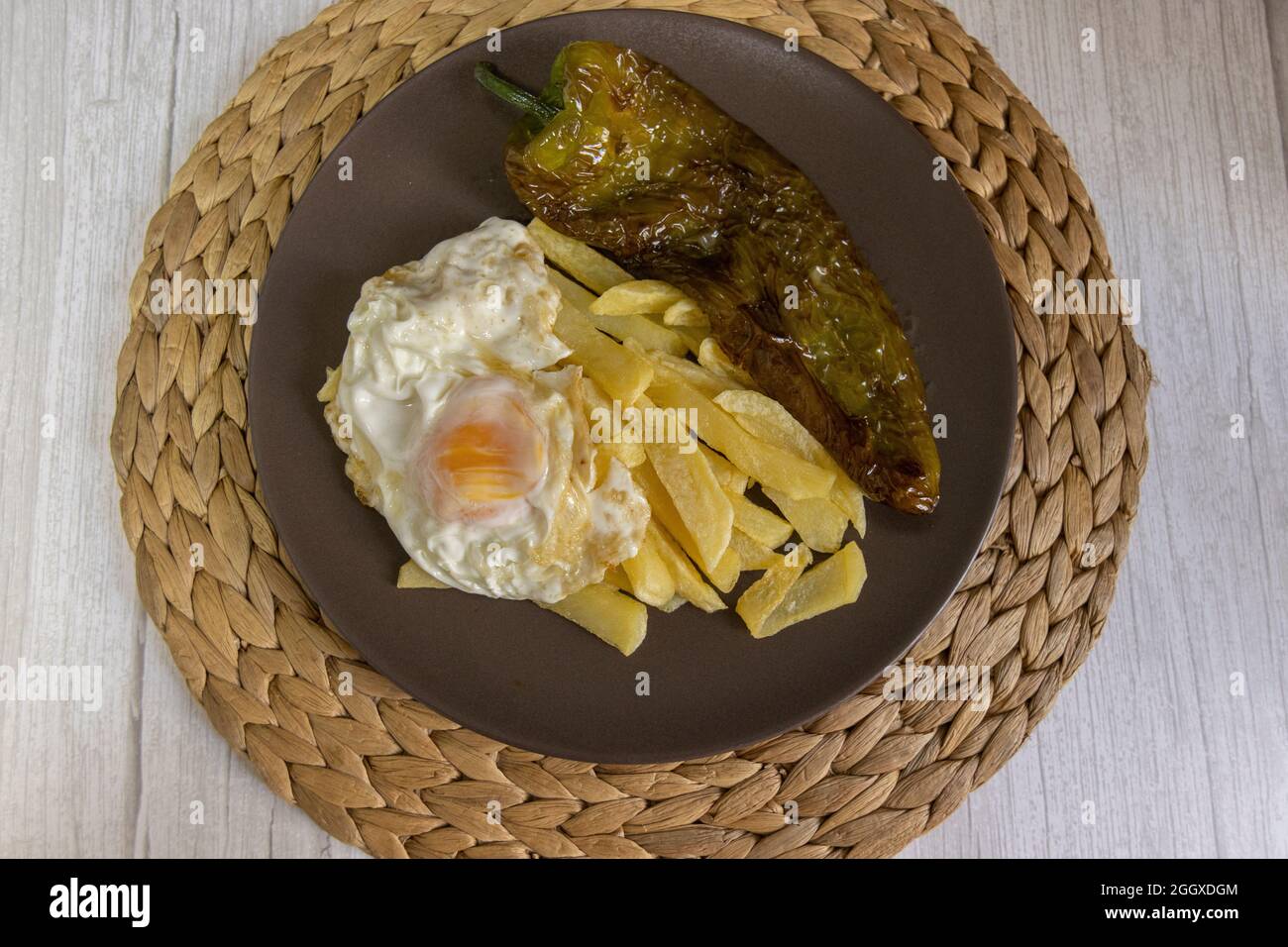 Patate fritte con uova fritte e pepe fritto, un alimento molto richiesto nel sud della Spagna. Tutto fatto con olio d'oliva. Vista dall'alto Foto Stock