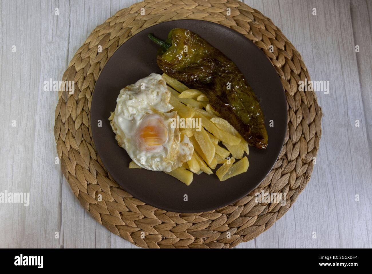 Patate fritte con uova fritte e pepe fritto, un alimento molto richiesto nel sud della Spagna. Tutto fatto con olio d'oliva. Vista dall'alto Foto Stock