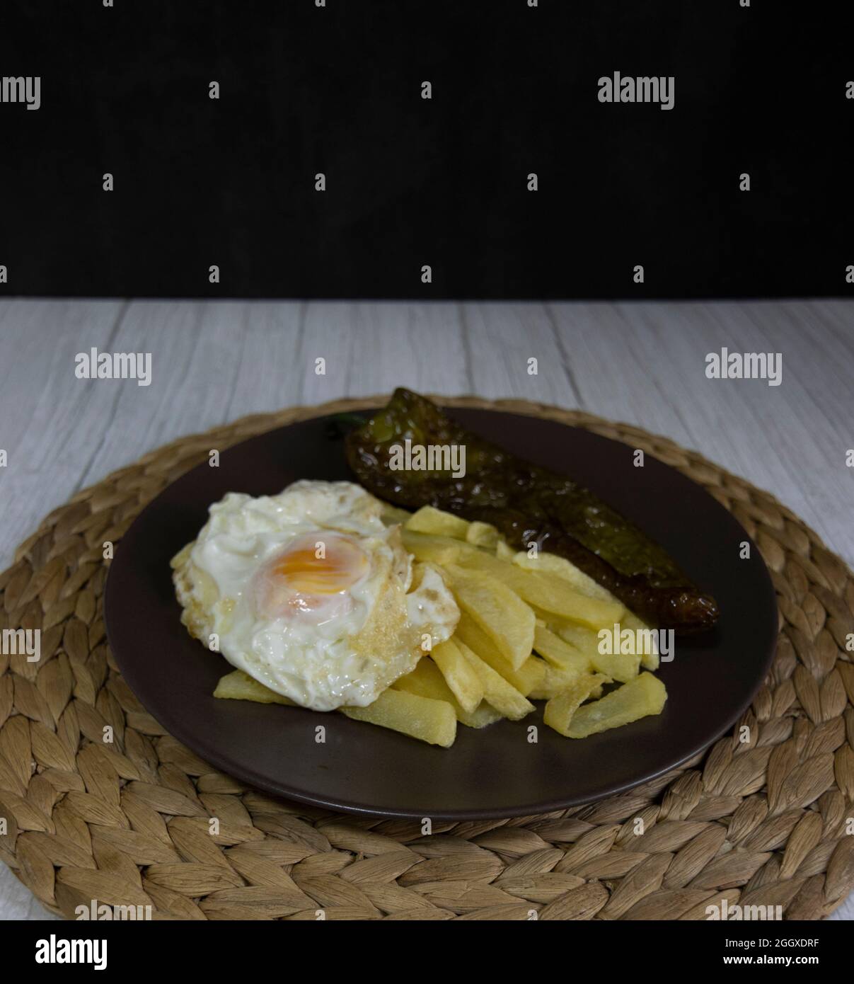 Patate fritte con uova fritte e pepe fritto, un alimento molto richiesto nel sud della Spagna. Tutto fatto con olio d'oliva. Vista dall'alto Foto Stock