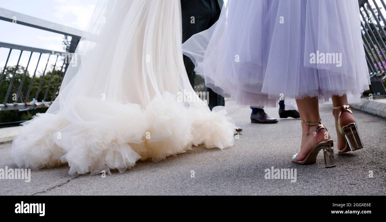 Dettagli del matrimonio: Classico abito da sposa in bianco e gambe di altri ospiti, vista a piano terra Foto Stock
