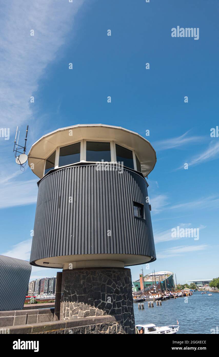 Amsterdam, Paesi Bassi - 15 agosto 2021: Torre di osservazione per la guardia del ponte sotto il paesaggio azzurro con il centro scientifico NEMO sul retro. Foto Stock