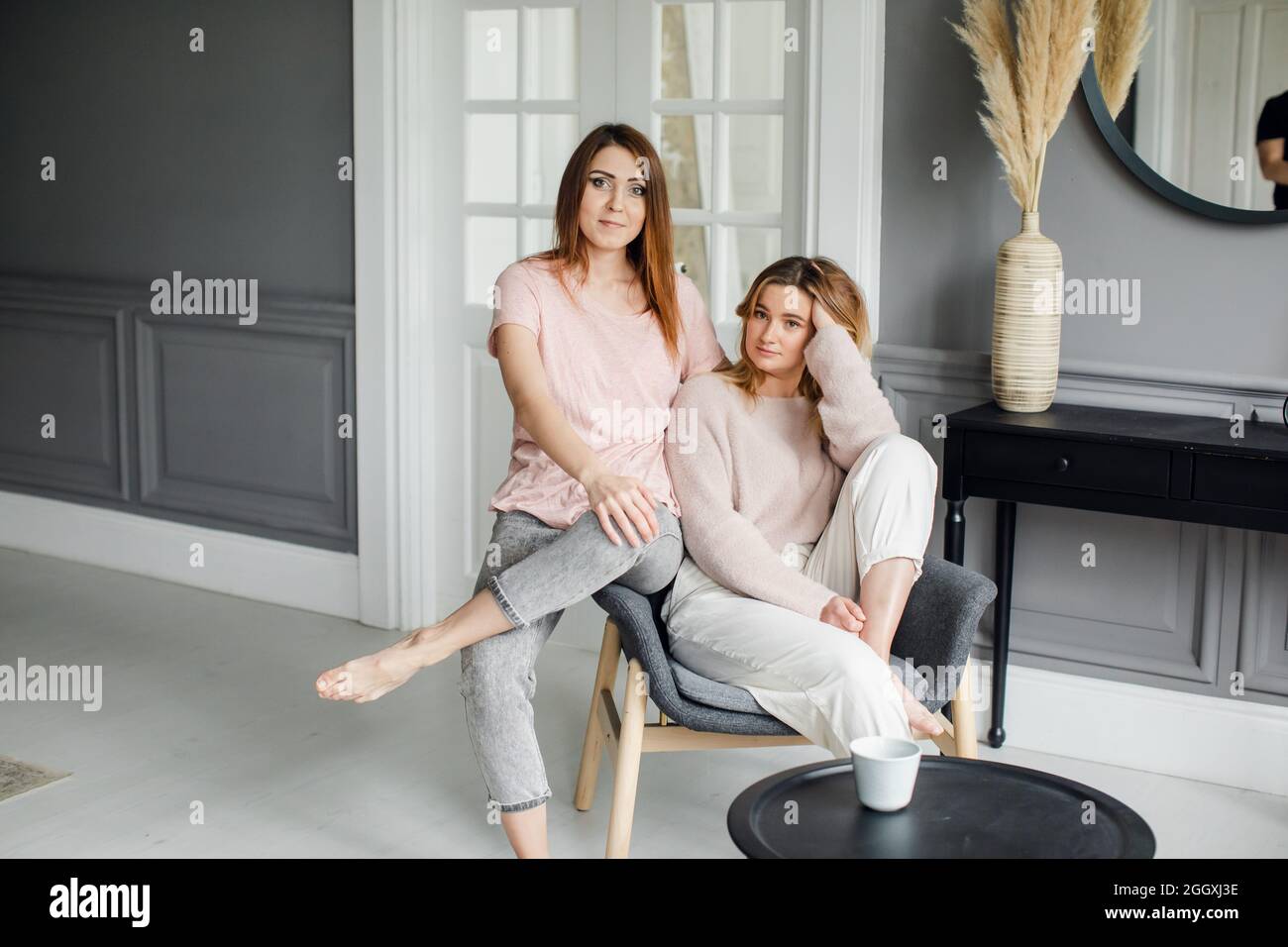 Due belle girlfriends seduti sul divano, che parlano eccitato, sorridente Foto Stock