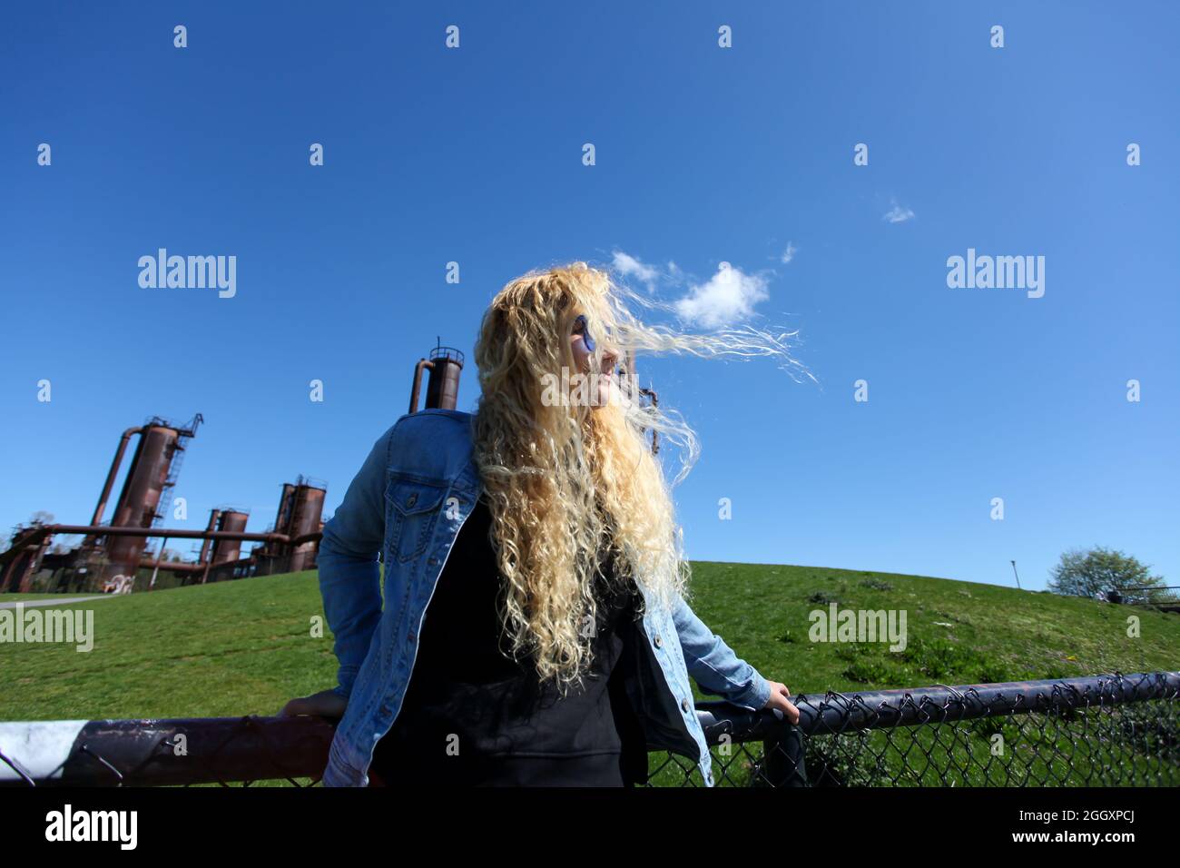 Capelli ricci biondi ispanica americana donna in piedi di fronte alla vecchia fabbrica a gas Works Park a Seattle. Foto Stock