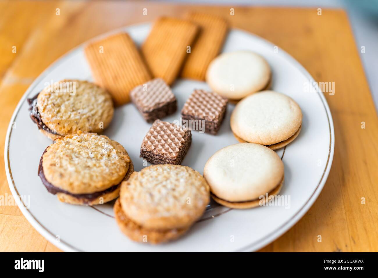 Assortimento di snack di biscotti gourmet al cioccolato con cialde e biscotti dolci con ripieno su piastra bianca macro closeup Foto Stock