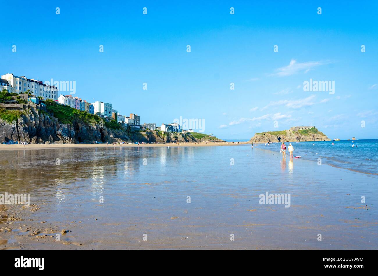 Una vista lungo la South Beach a Tenby in Galles, Regno Unito con l'Isola di St Catherine sulla destra ed edifici colorati sull'Esplanade sulla sinistra. Foto Stock