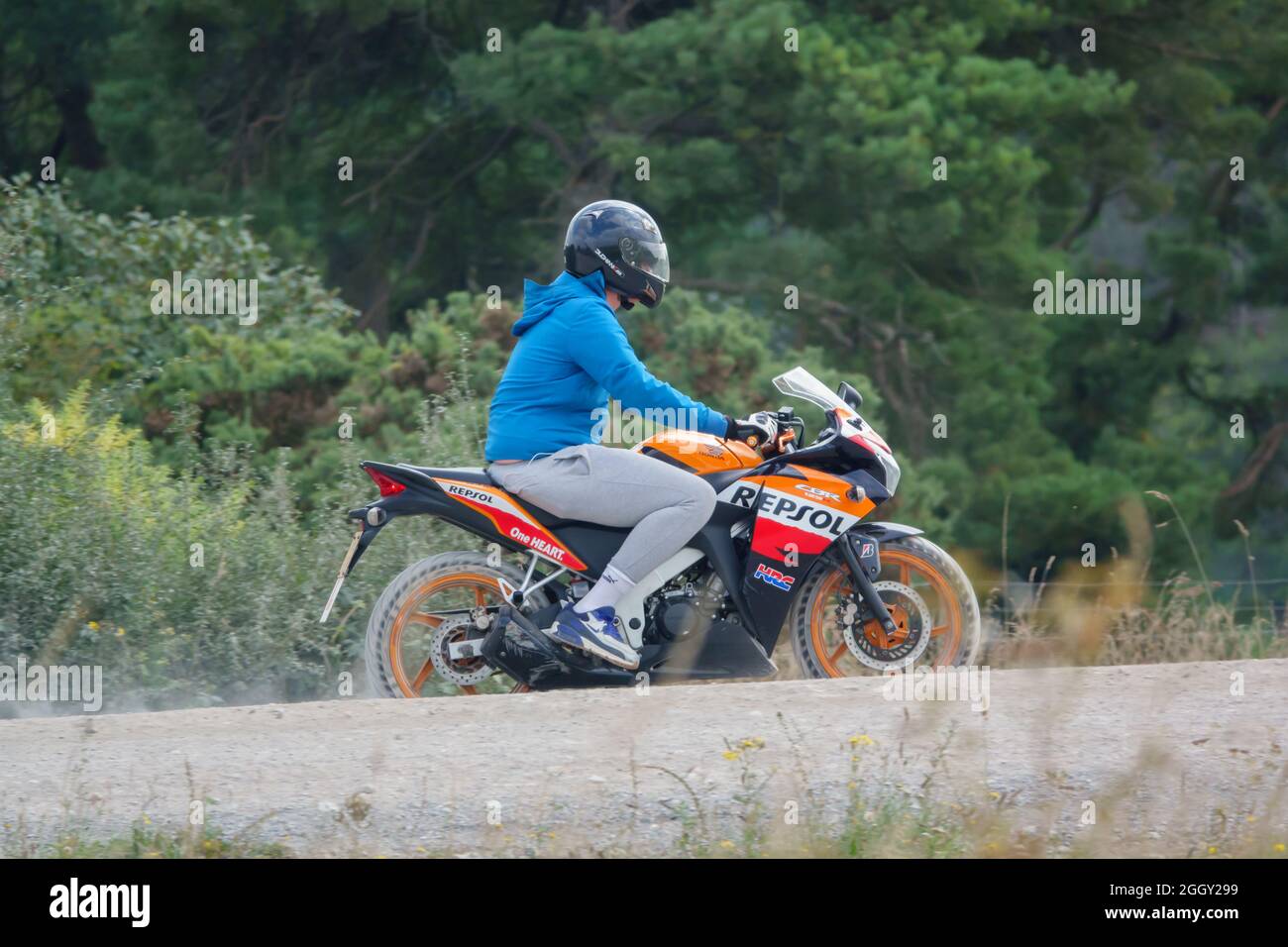 Motociclista studente che viaggia su una pista di polvere sulla sua moto liveried Repsol, Wiltshire UK Foto Stock