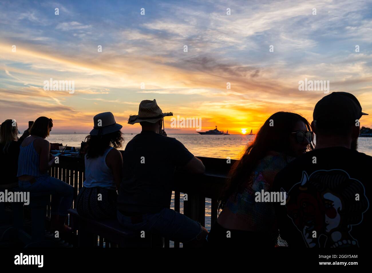 Key West, USA - 24 gennaio 2021: Silhouette di persone che guardano il tramonto da Mallory Square, Florida da sole colorato in cielo nuvoloso blu Foto Stock