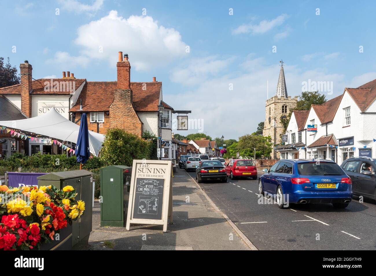 Vista della High Street nel villaggio di Chobham, Surrey, Inghilterra, Regno Unito, con le imprese, Il Sun Inn e la Chiesa di San Lorenzo Foto Stock