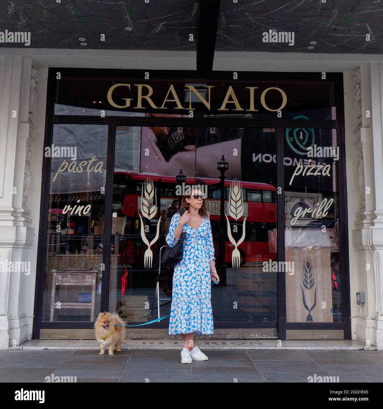 Londra, Greater London, Inghilterra, 24 2021 agosto: Donna in piedi con un cane in testa davanti a un negozio di Piccadilly Circus. Foto Stock