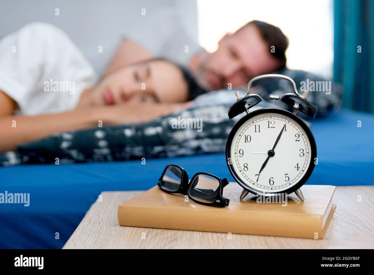 Coppia che dorme nel letto. Sveglia sul comodino. Concetto di sonno sano Foto Stock