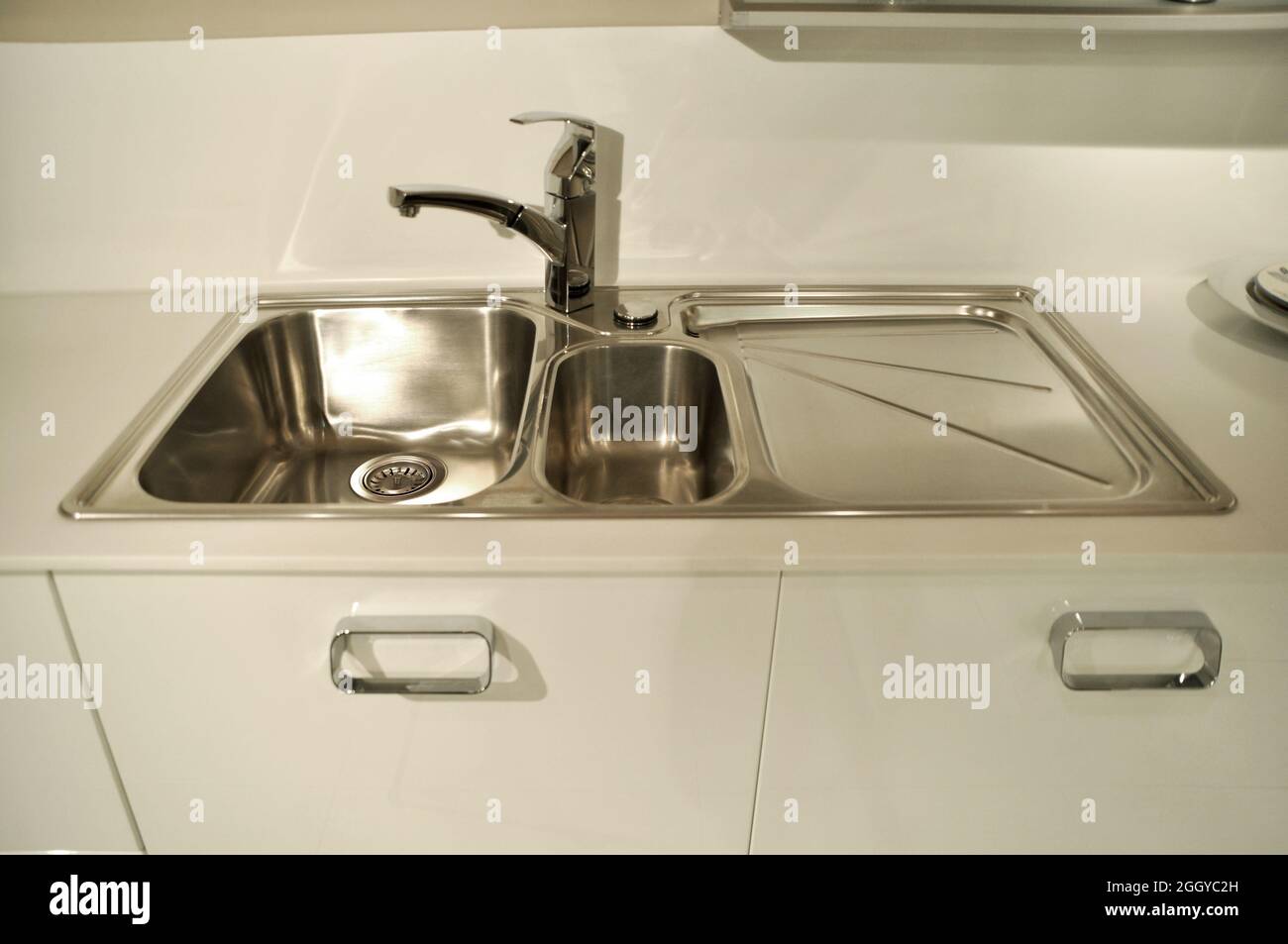 Interno di lussuosa cucina moderna e lavandino, rubinetto e scarico in acciaio inossidabile Foto Stock