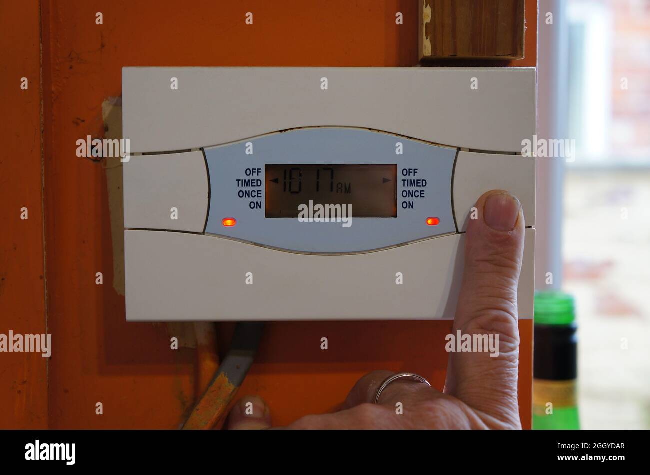 Pressione con un dito di un tasto su un comando di riscaldamento centralizzato in casa Foto Stock