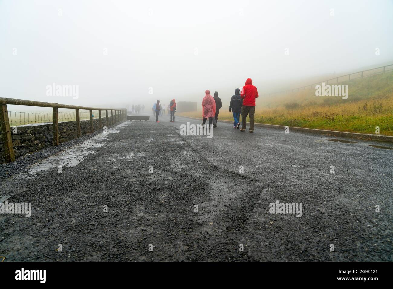 Scogliere di Moher Irlanda - Agosto 11 2017; gruppo di turisti che si dirigono a piedi verso le scogliere di Moher in inverno foggy giorno vestito con abbigliamento tempo umido Foto Stock