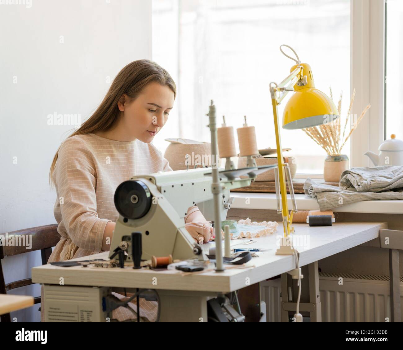 I vestiti da cucire femminili messi a fuoco sul suo posto di lavoro Foto Stock