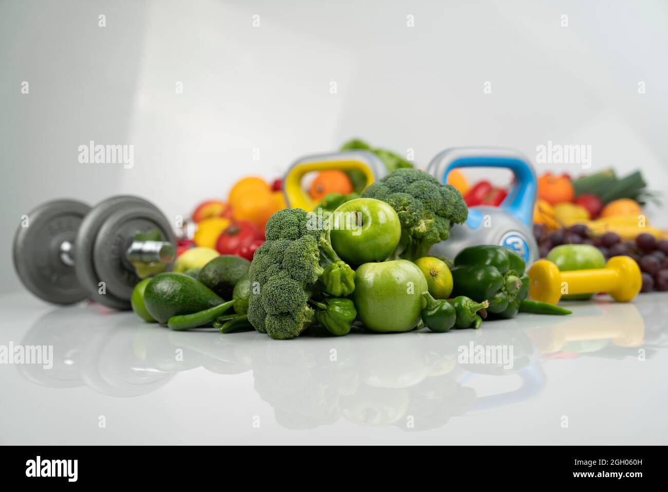 Concetto di fitness. Alimentazione sana: Frutta e verdura. Attrezzature per esercizi di fitness: Pesatrice e manubri. Sfondo bianco. Foto Stock