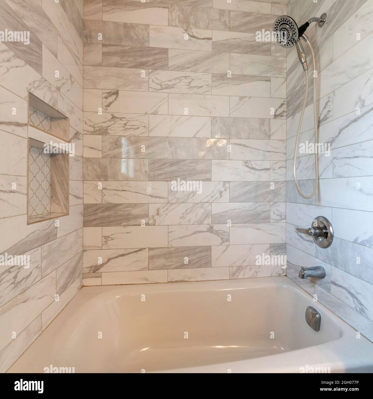 Moderno bagno interno a cornice quadrata con vasca da bagno in alcova e piastrelle in marmo circondate Foto Stock